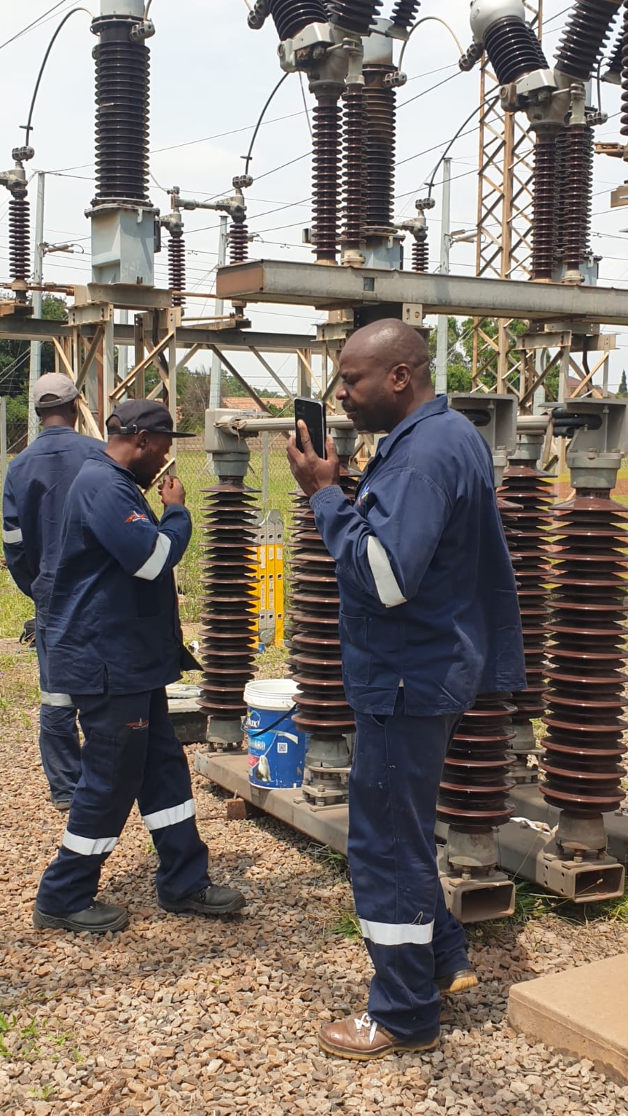 Harnessed technicians installing insulator connections