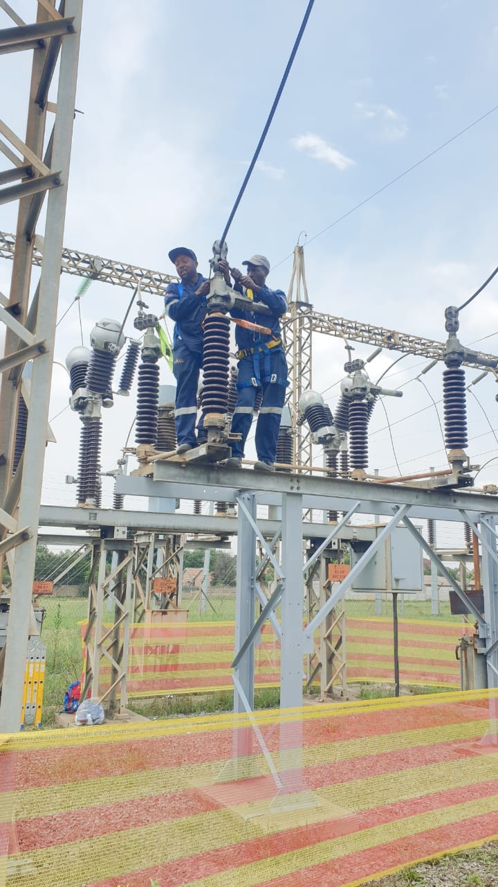Technicians working on high-voltage insulators at Tosa Substation